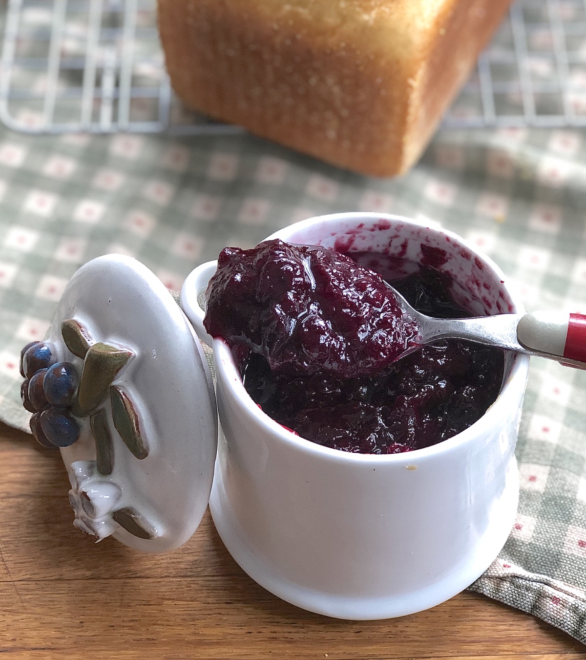 Jam jar or blueberry jam with decorative lid and spoon.