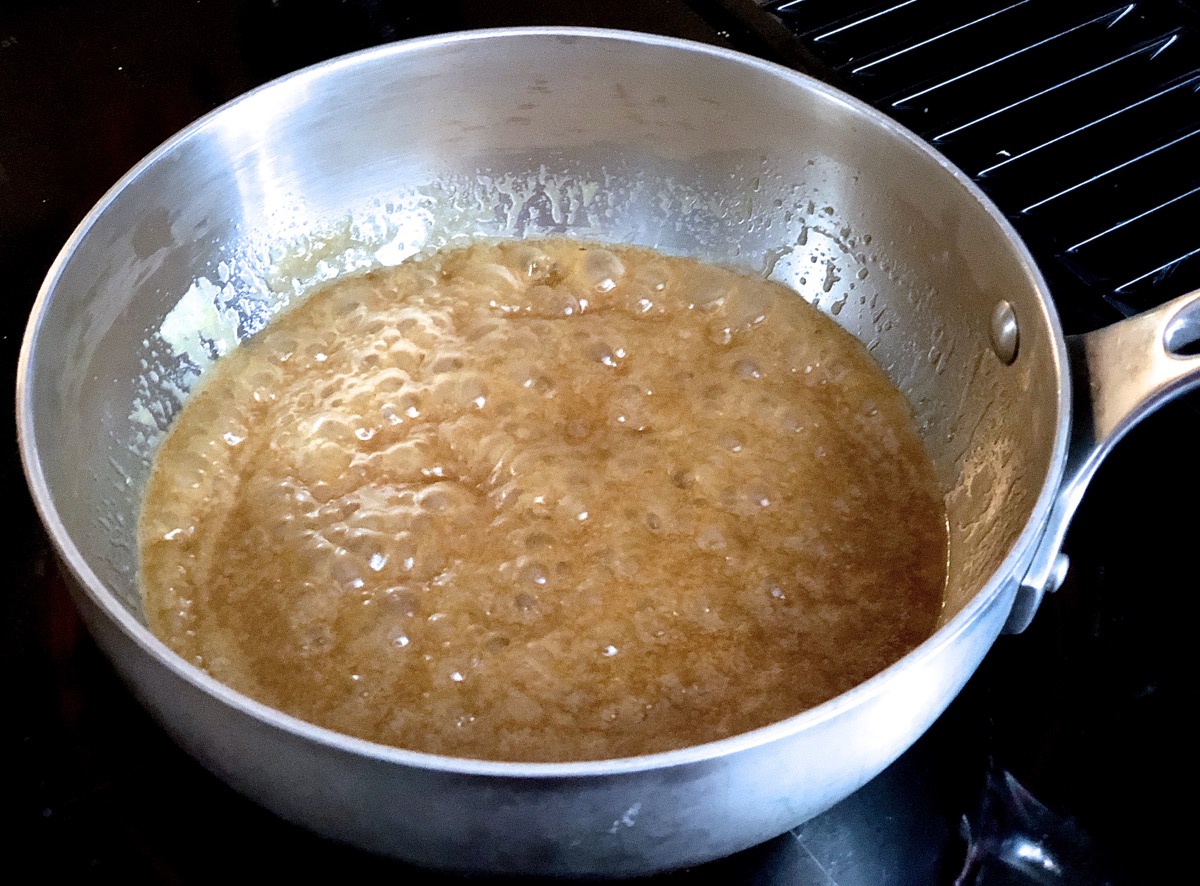 Brown sugar frosting simmering in a saucepan on the stovetop.
