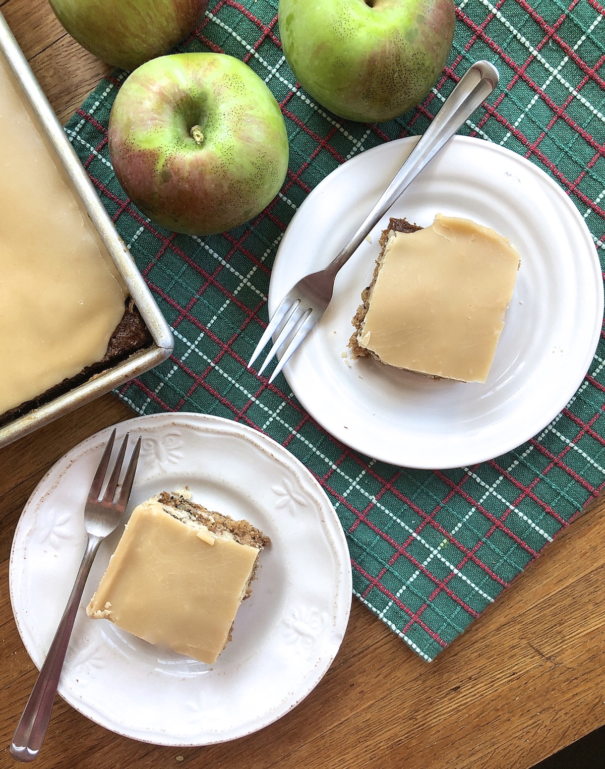 Apple cake with brown sugar frosting cut into squares and served on plates.