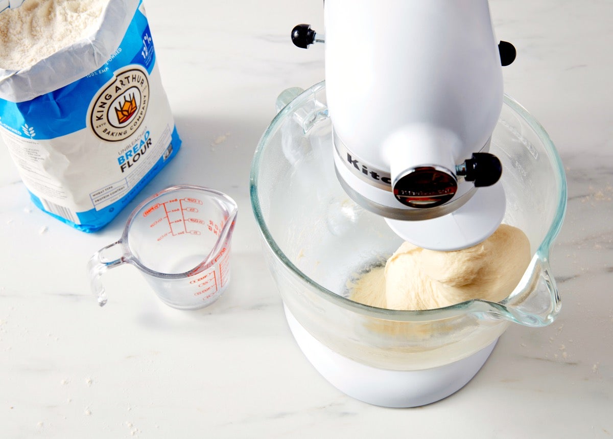 Cinnamon roll dough in the bowl of a stand mixer, bread flour bag alongside.