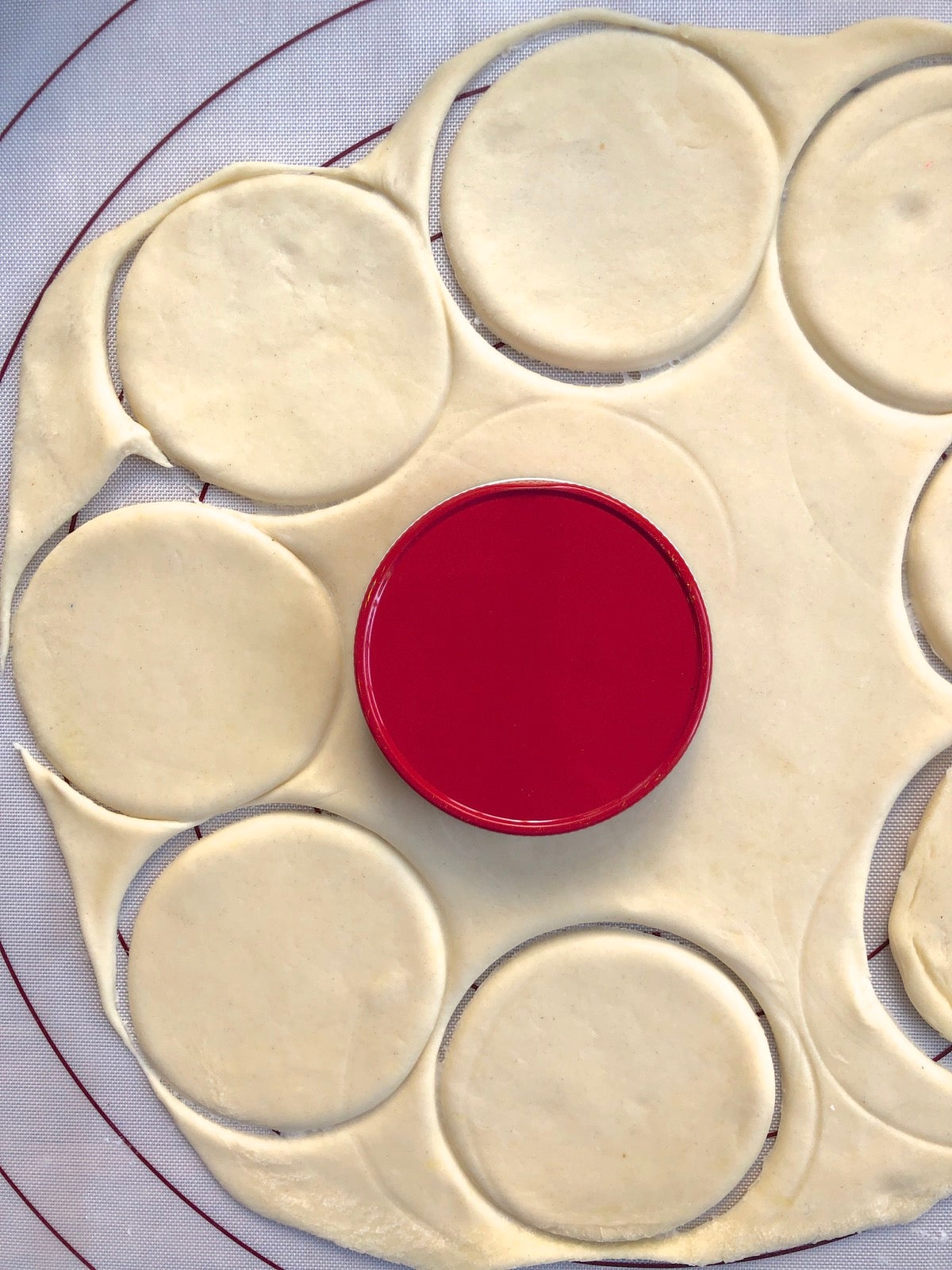 Pierogi dough rolled into a circle, and smaller circles being cut from the dough with a jar lid.