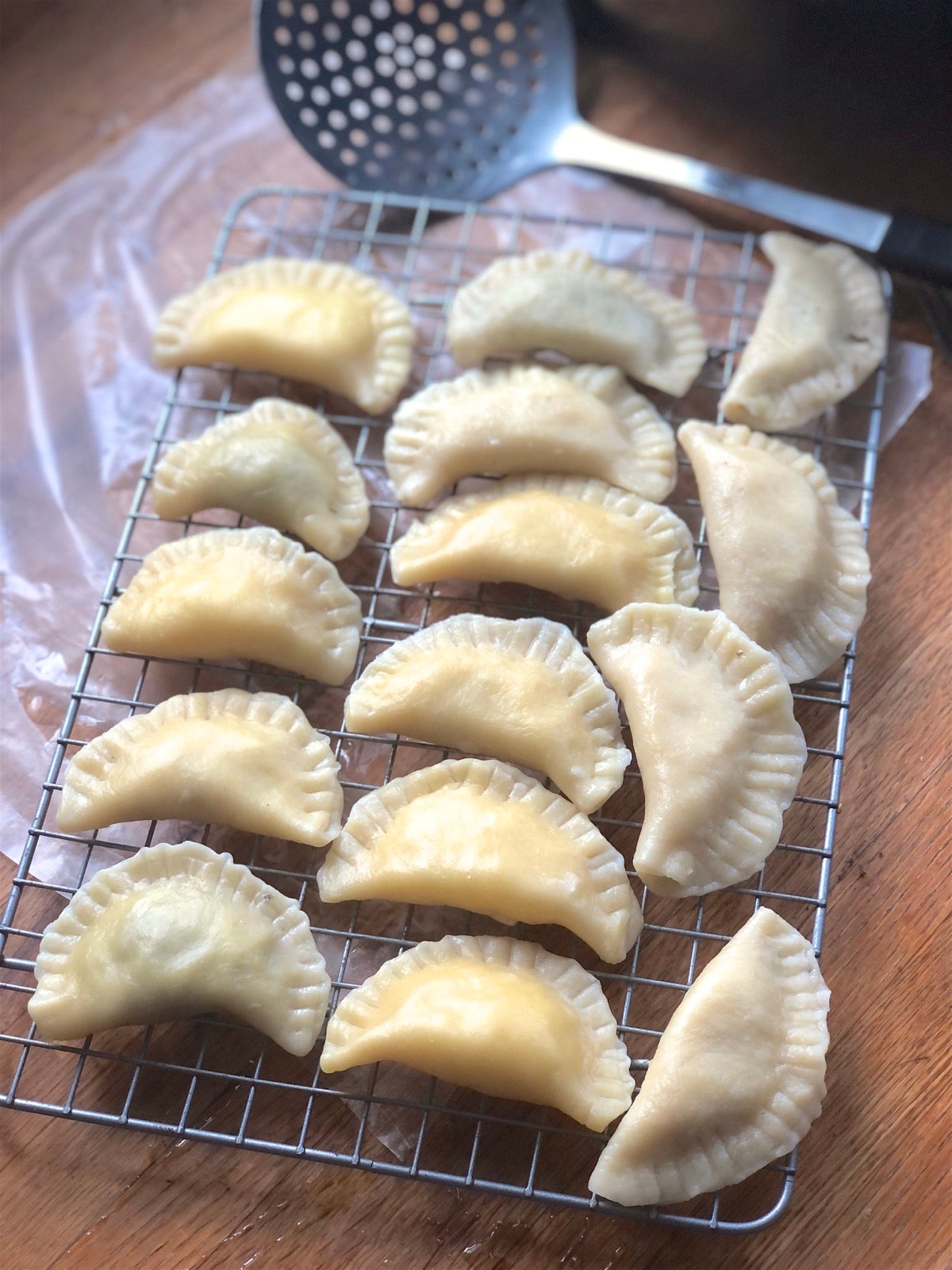 Boiled pierogi cooling on a rack prior to being fried with onions.