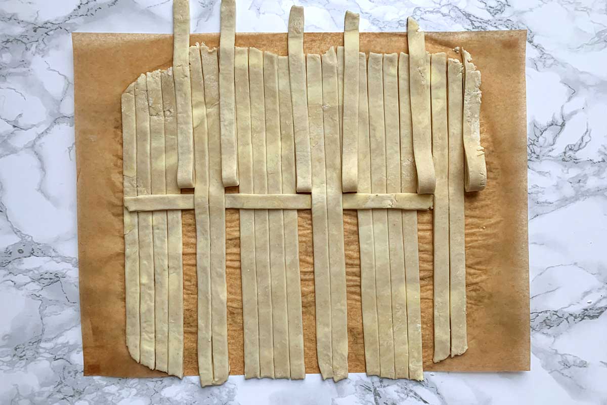 Same sheet of dough as previous image, with middle two strips in each group unfolded over horizontal strip