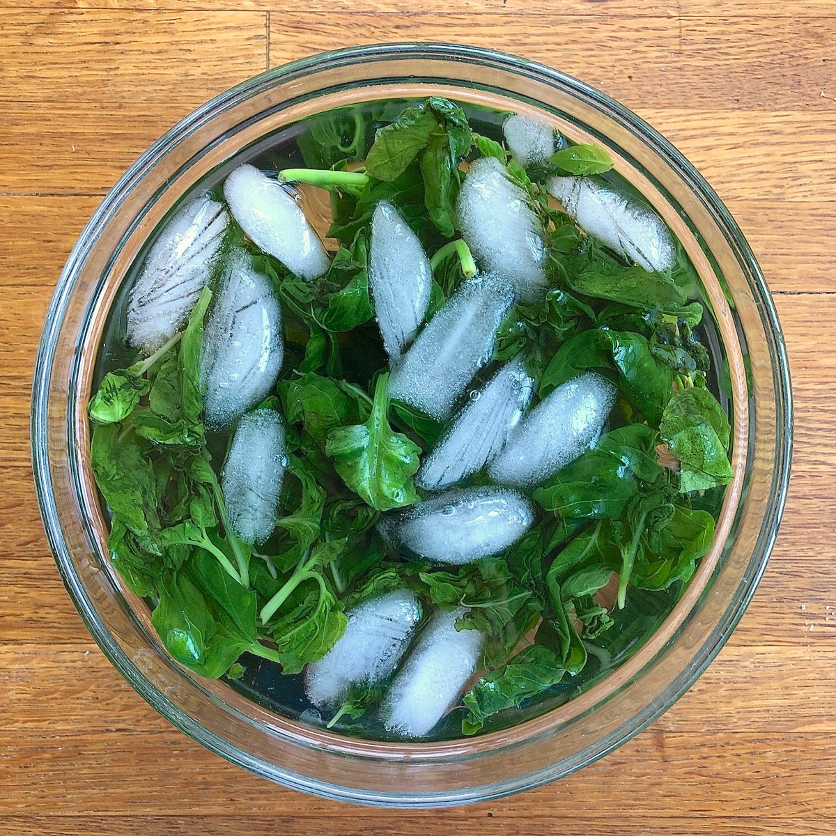 Blanched fresh basil leaves cooling in an ice water bath.
