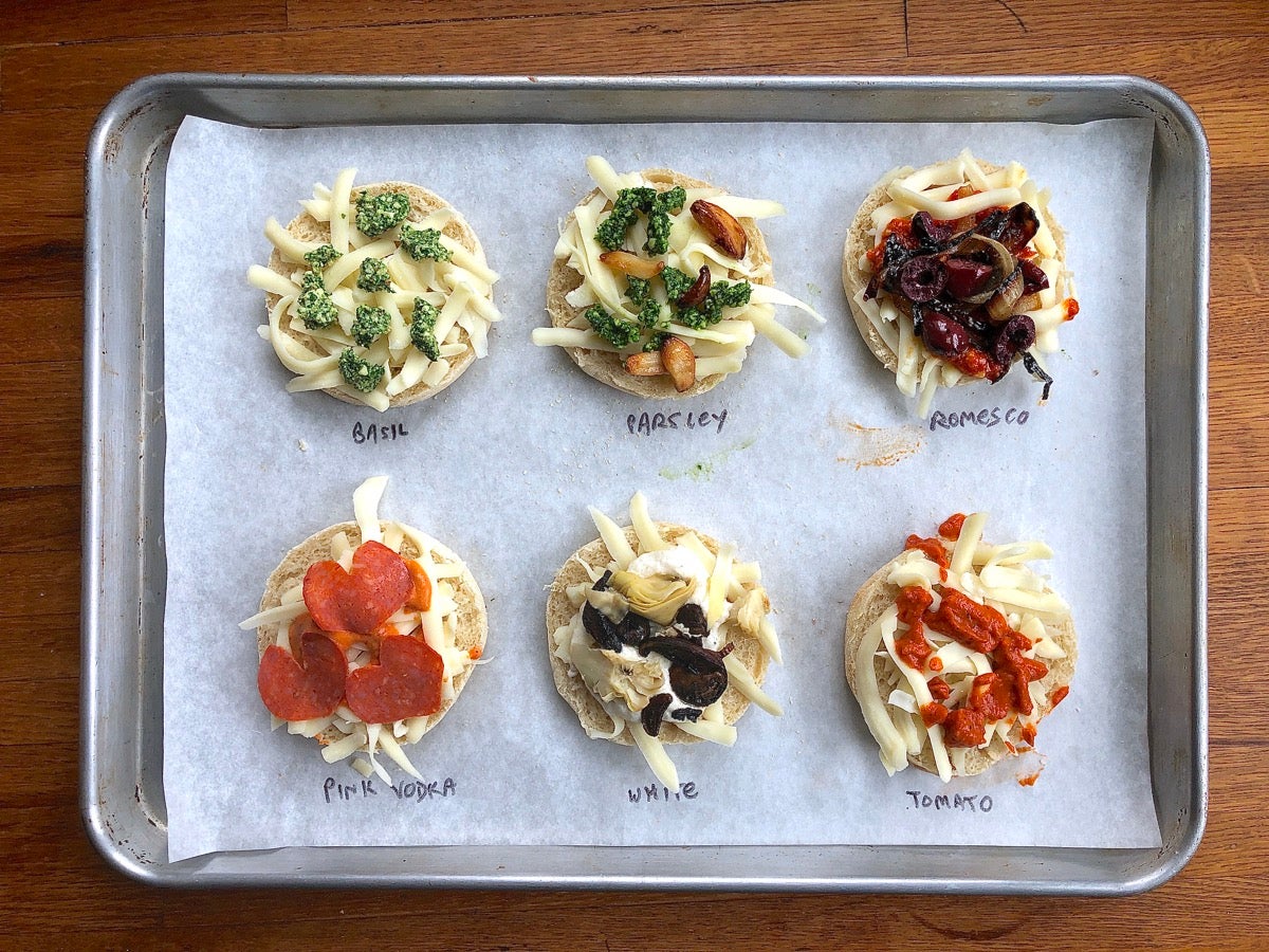 Testing six different sauces on English muffin halves; all lined up on a baking sheet ready to go into the oven.
