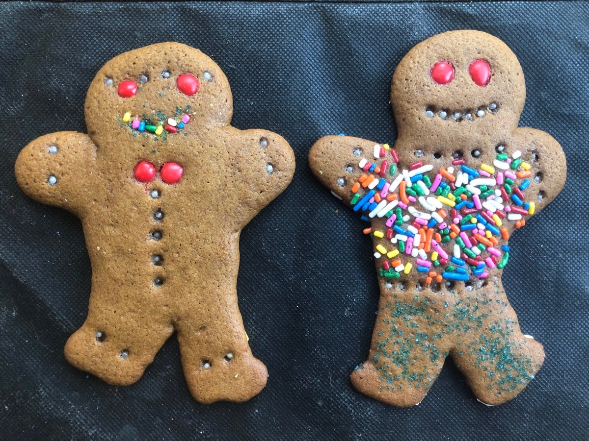 Two decorated gingerbread men on a black cloth.