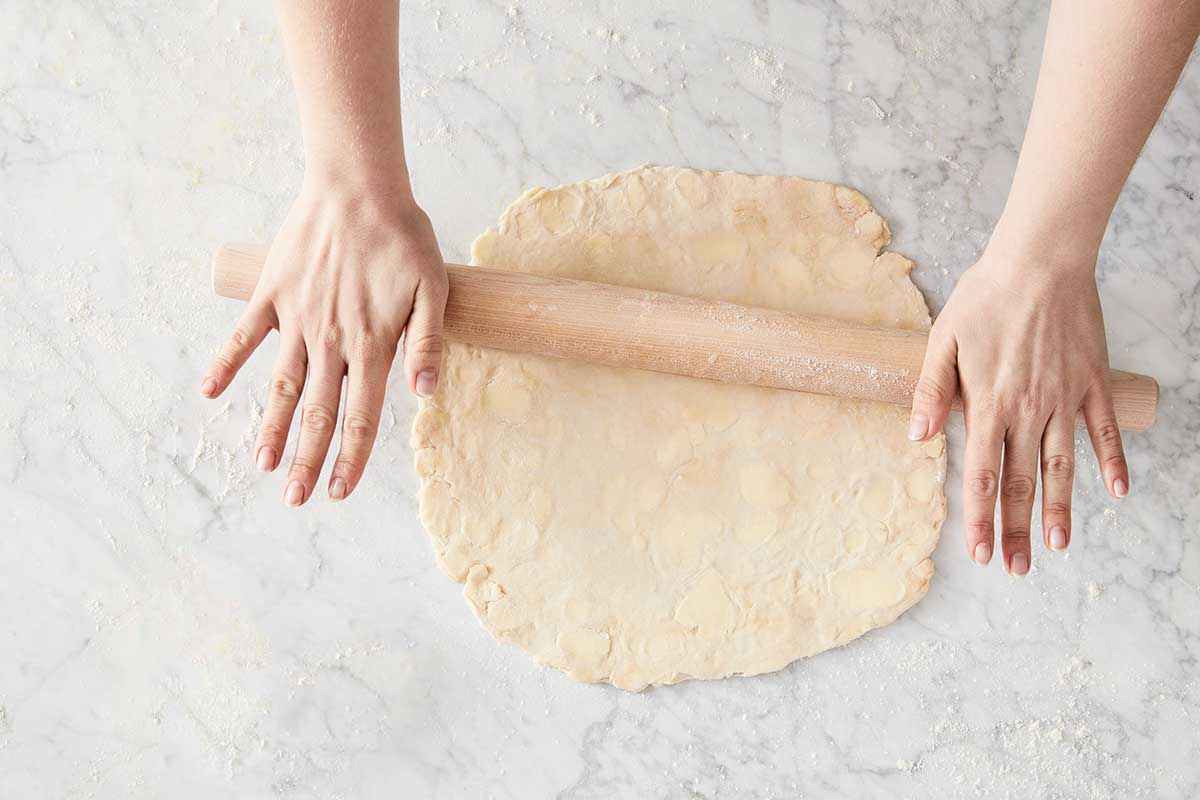 A baker rolling out a single pie crust