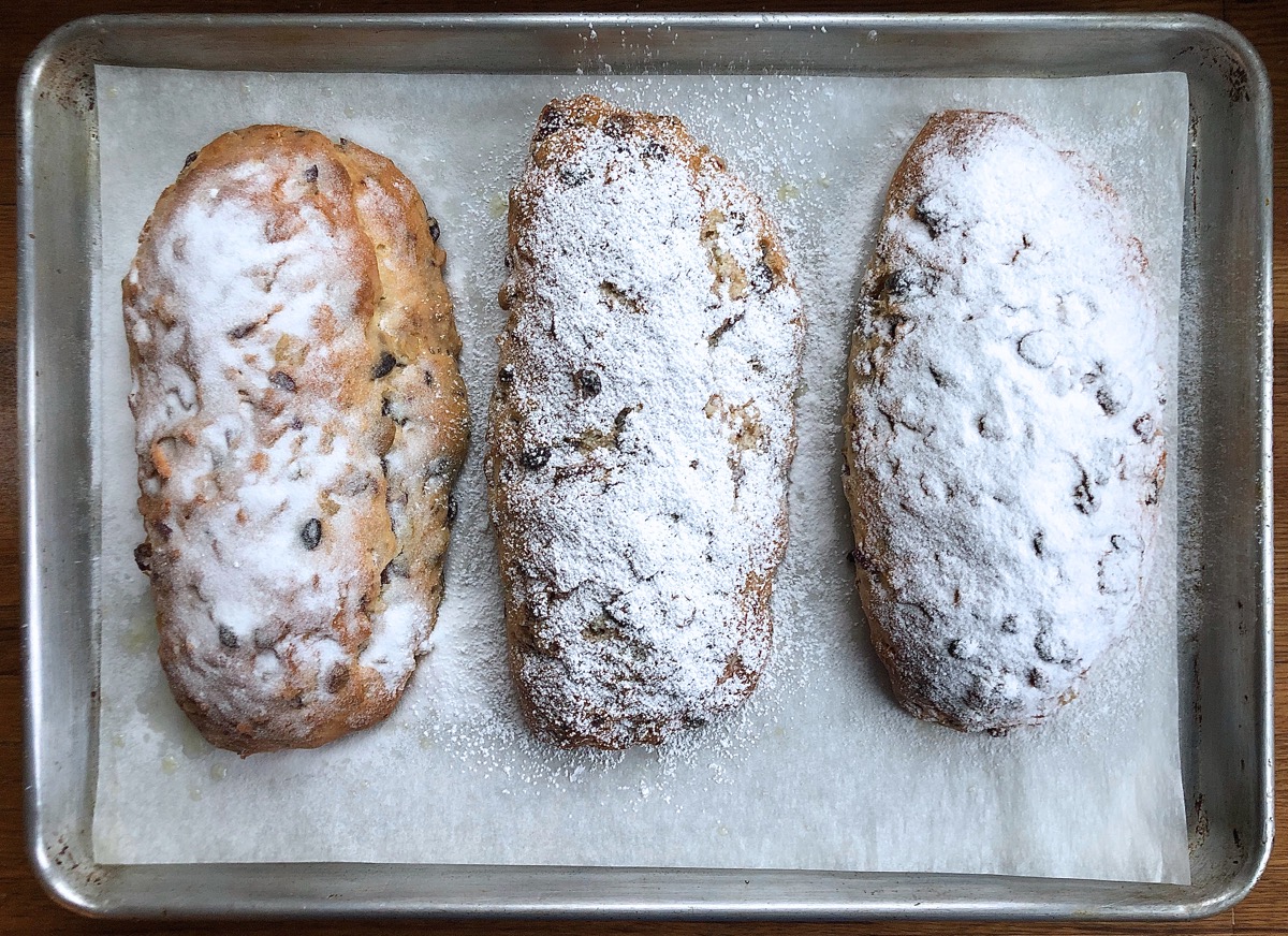 Three stollen showered with sugar, cooling on a rack.