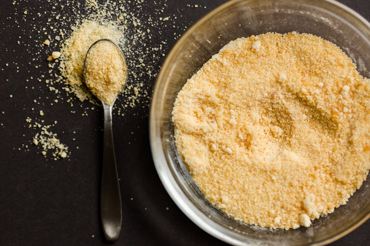 A spoon and bowl of toasted sugar on a dark table