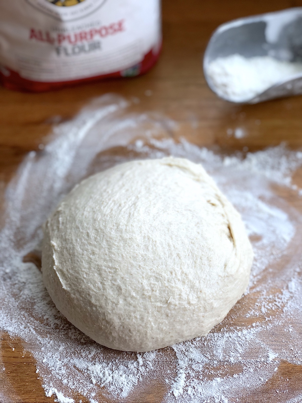 Dough made from yeast water starter on a floured wooden kneading surface.