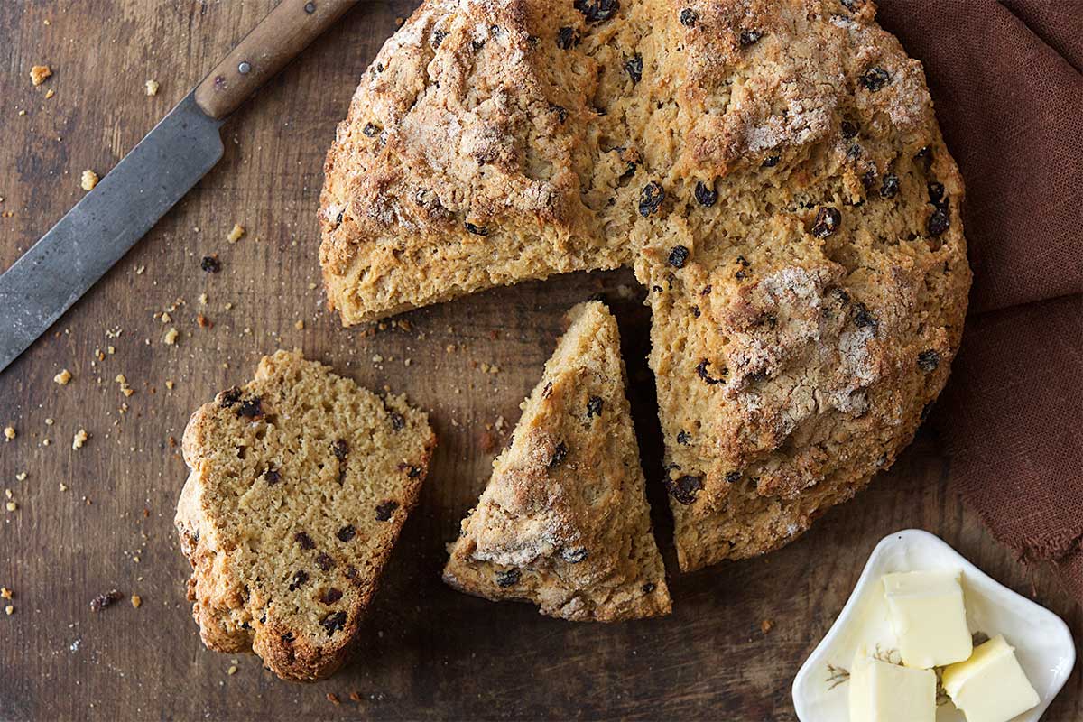 A loaf of Irish soda bread with a wedge cut out of it
