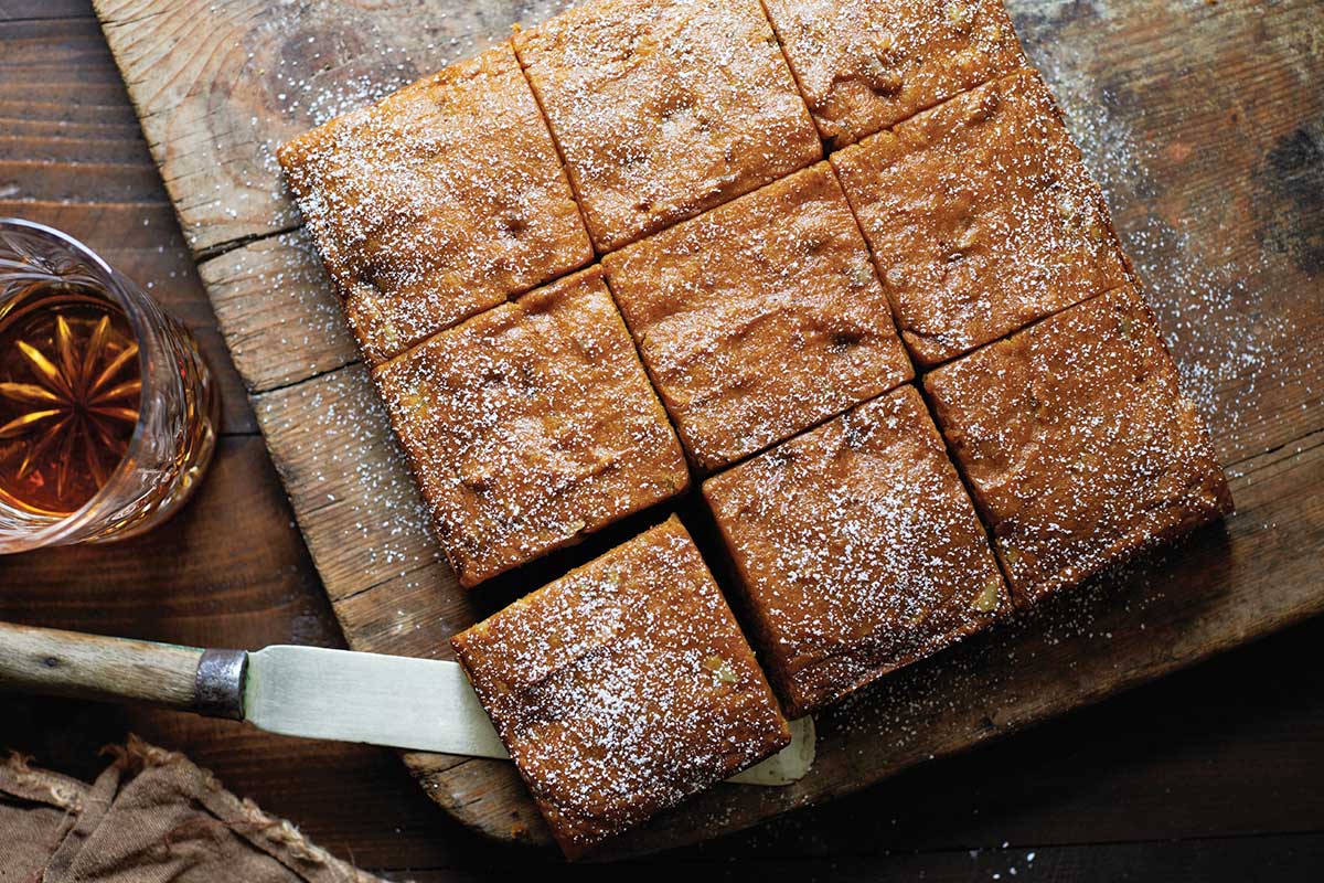 A pumpkin spice cake pan cake cut into slices and topped with confectioners' sugar