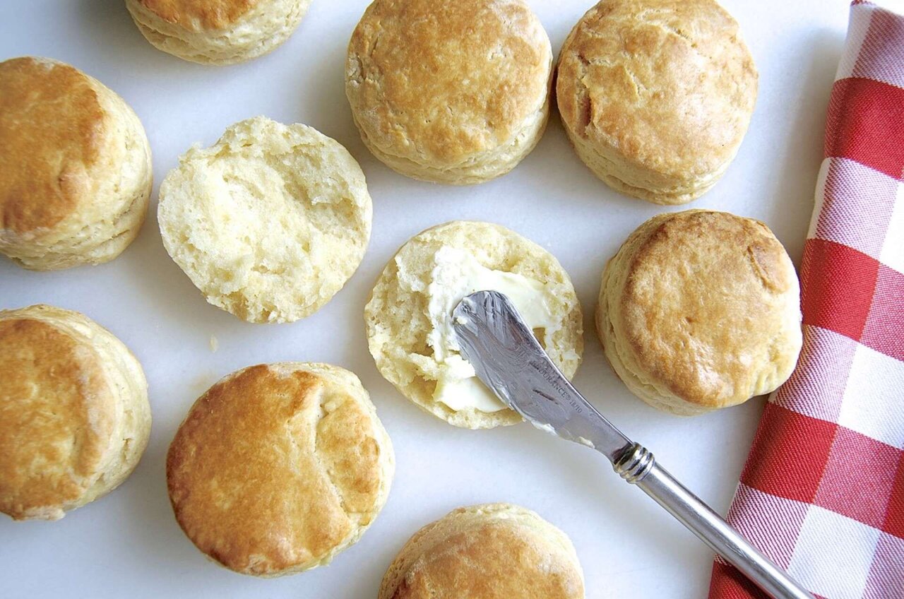 Biscuits on a baking sheet, with one split and buttered 