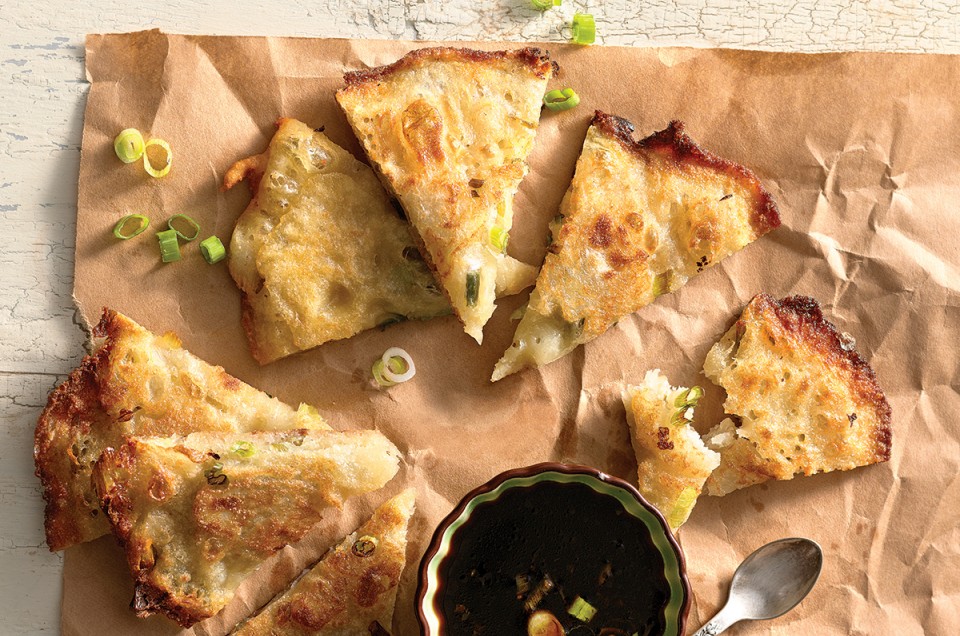 Scallion pancakes cut into wedges with a side of dipping sauce
