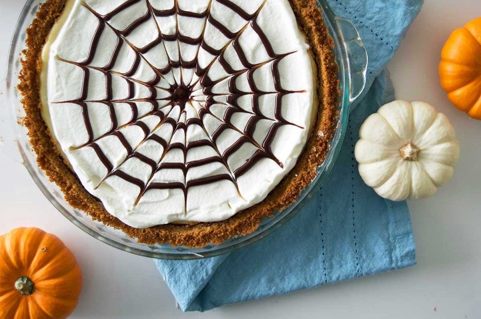 Spider web cheesecake surrounded by mini pumpkins