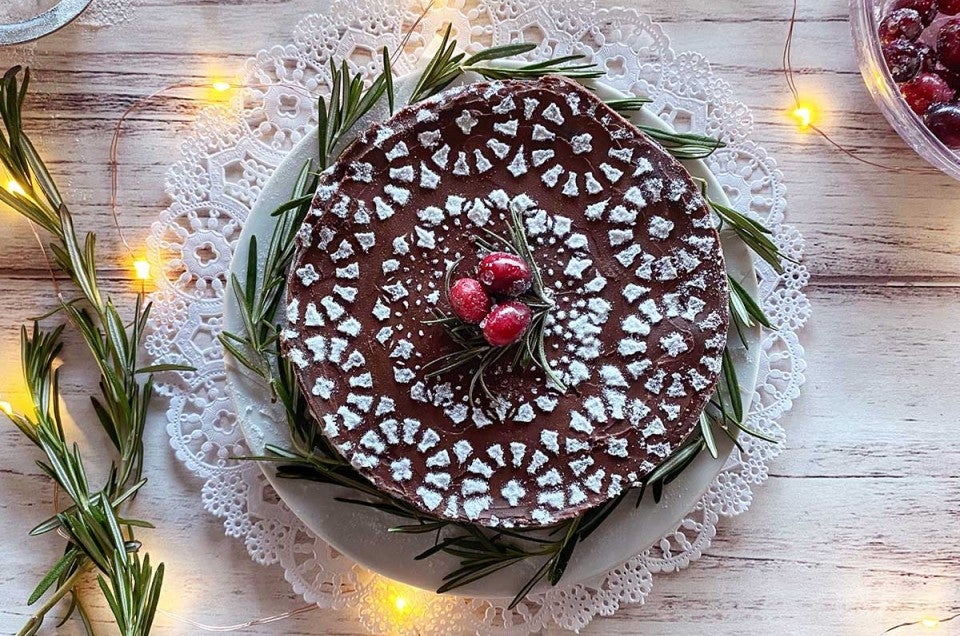 A flourless chocolate cake stenciled with confectioners' sugar, cranberries, and twinkling lights