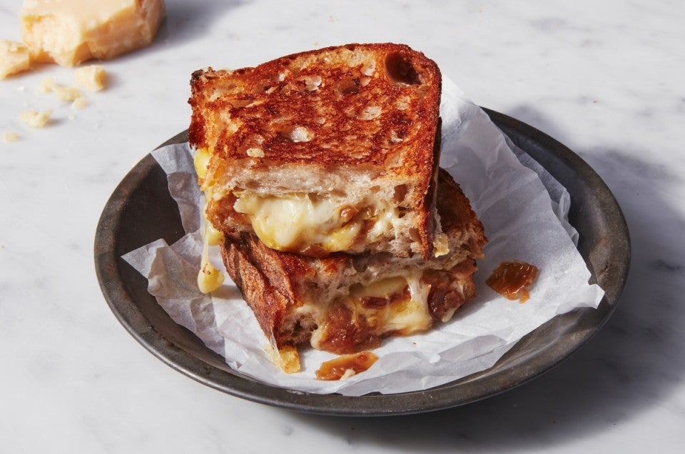 French onion grilled cheese sandwich cut in quarters, two pieces stacked on a plate