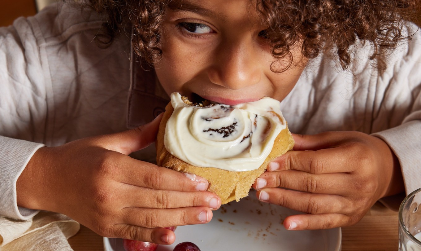 A young child indulging in a cinnamon bun