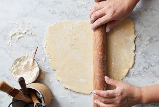 Hands rolling out pie crust