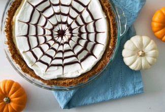 Spider web cheesecake surrounded by mini pumpkins