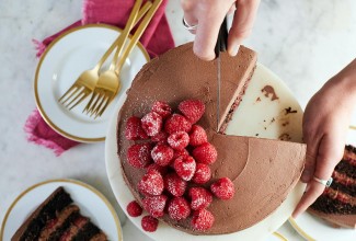 A chocolate mousse cake with raspberries being sliced