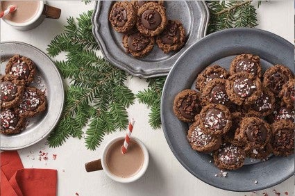 Hot Cocoa Cookies on a plate with cups of hot cocoa.