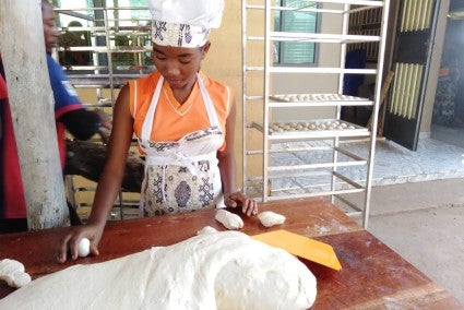 Baker dividing bread dough and rolling loaves