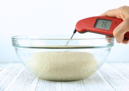 Thermometer probe placed into the center of a bowl of just-kneaded dough showing a dough temperature of 75°F.