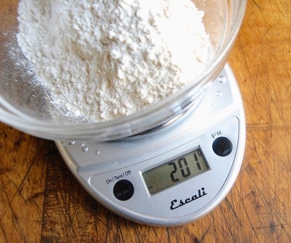 Digital scale with a bowl of flour on the weighing platform.