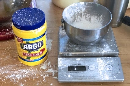 Scale and container of cornstarch on countertop, cornstarch spilled all over everything