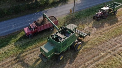 Aerial view of a combine loading grain into a farm trailer