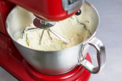 Stand mixer bowl showing sandy mixture of butter beaten into dry ingredients