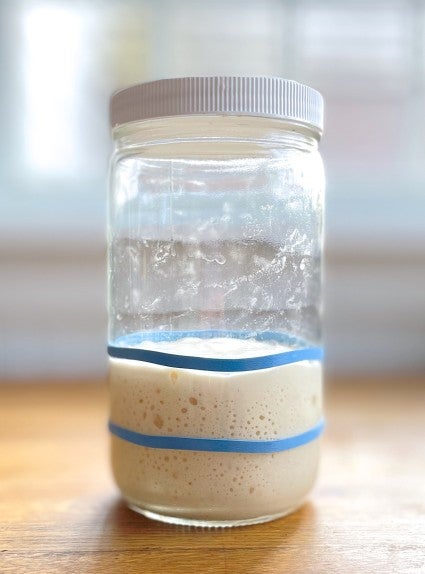 Fed sourdough starter in a clear glass jar.
