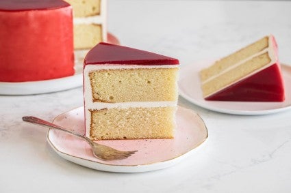 A slice of cake topped with raspberry mirror glaze