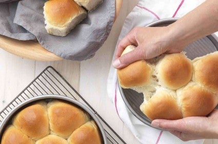 Golden Pull-Apart Butter Buns in three round pans, being pulled apart