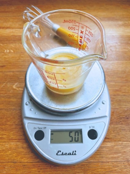 Measuring cup on a scale with beaten egg.