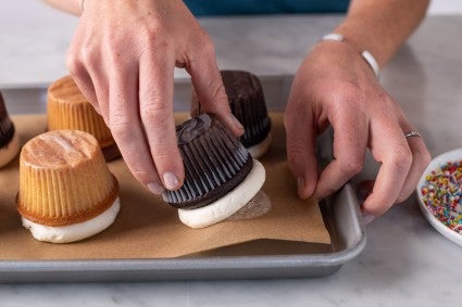 A baker turning over a cupcake after the frosting has been flattened and chilled upside down