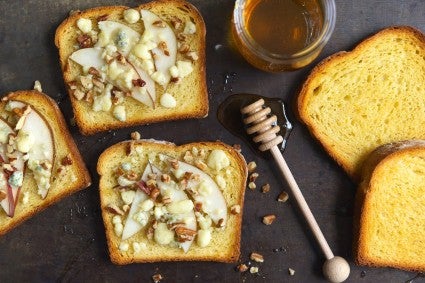 Loaf of golden potato sandwich bread, sliced, some slices layered with apple slices, blue cheese, and nuts