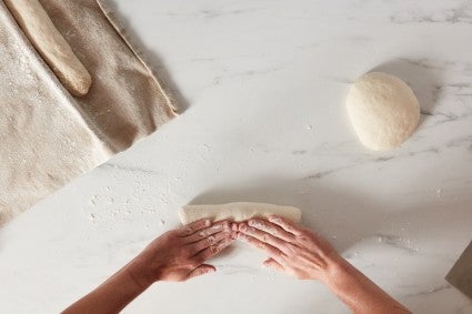 Baker folding baguette dough to shape