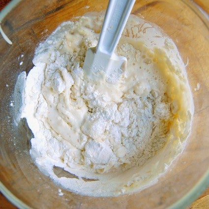 Feeding sourdough starter by stirring in flour and water.