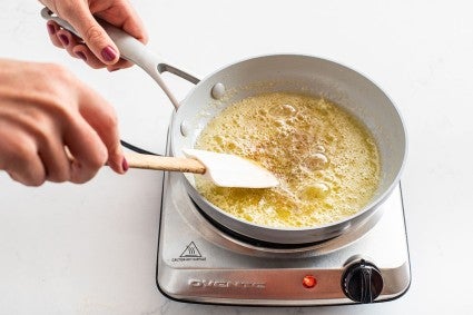 A baker browning butter in a saucepan