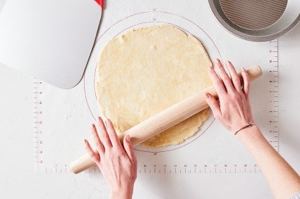 Baker using a French rolling pin to roll out pie dough