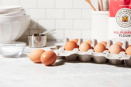 A dozen eggs on the kitchen counter next to a bag of King Arthur Flour