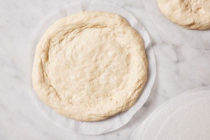 Shaped round of unbaked pizza dough