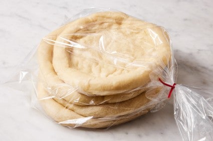 Rounds of parbaked pizza crust in a plastic, freezer-safe bag