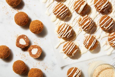 Eggnog truffles drizzles with glaze, some broken in half to reveal a creamy center